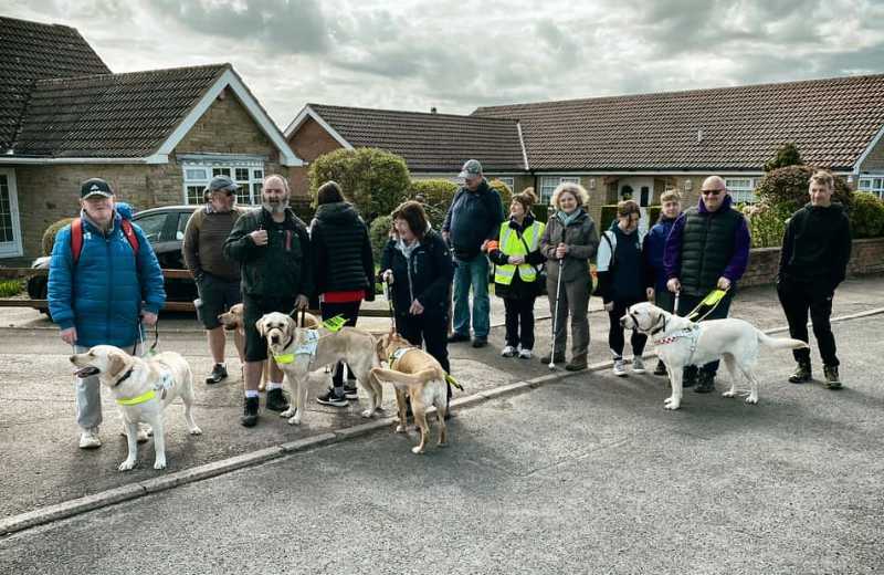 Coastline Sight and Hearing group photo of members and guide dogs at the Cindertrack in Scalby