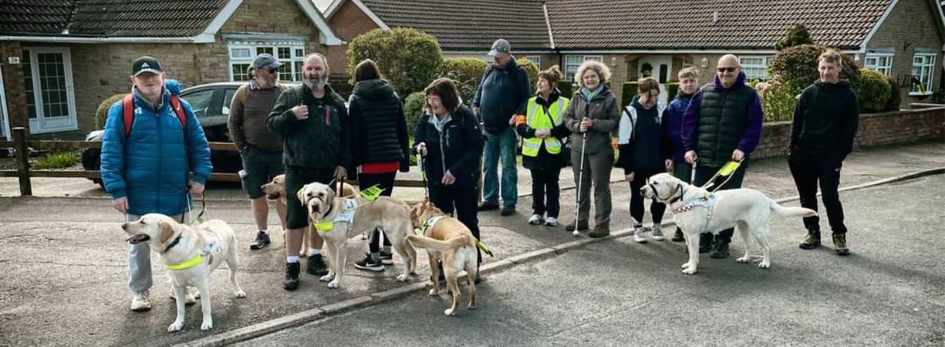 Coastline Sight and Hearing group photo of members and guide dogs at the Cindertrack in Scalby